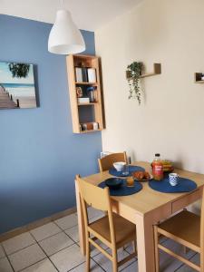 a dining room table with chairs and a blue wall at Résidence les aloès T2 / 4 personnes 2min à pied de la mer in Cerbère