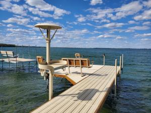 a dock with two chairs and a table on the water at Sandy Beach Retreat on Big Spirit Lake in Spirit Lake
