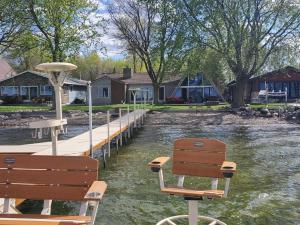 a wooden dock with two benches next to a body of water at Sandy Beach Retreat on Big Spirit Lake in Spirit Lake