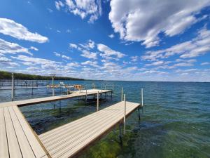 a dock on a body of water with a cloudy sky at Sandy Beach Retreat on Big Spirit Lake in Spirit Lake