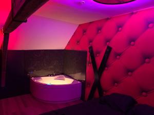 e bagno con illuminazione rosa e vasca. di Love room avec jacuzzi privé a Bonnétable