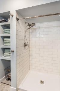 La salle de bains est pourvue d'une douche et d'un mur carrelé blanc. dans l'établissement Sandy Feet Retreat on Big Spirit Lake, à Spirit Lake 31 autres photos