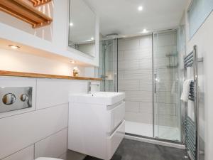 La salle de bains blanche est pourvue d'une douche et d'un lavabo. dans l'établissement 7 Valley View, à Looe