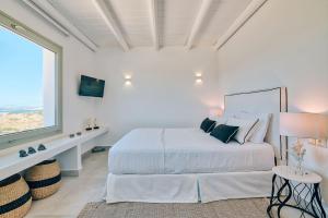 a white bedroom with a large bed and a window at Antiparos Thea in Antiparos