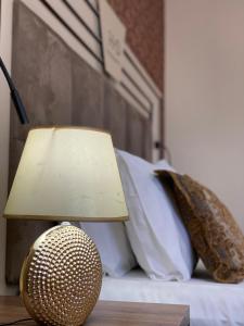 a lamp on a table next to a bed with pillows at Hotel Deluxe in Tirana