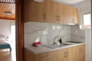 una cucina con armadi in legno e lavandino di Dream Apartments a Paralia Dionysiou