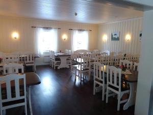 un comedor con sillas blancas, mesas y mesa en Badeland Gjestegård, en Raufoss