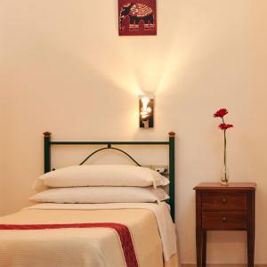 Un dormitorio con una cama y un jarrón con una flor en Cagliari Novecento, en Cagliari