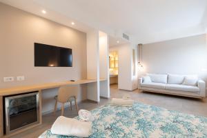 Molo Brin Rooms & Suites في أولبيا: غرفة معيشة مع أريكة وتلفزيون على الحائط