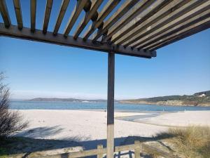 a view of a beach with a wooden pergola at Casa con encanto en Laxe in Laxe +10 photos