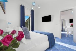 a bedroom with a bed with roses and a television at BlueVista Dreamscape Home -Terrace Jacuzzi/Hot Tub in Positano