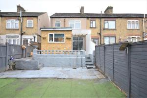 una valla frente a una casa con edificios en 4 Bedroom House in East London, en Londres