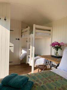 a bedroom with two bunk beds and a desk with flowers at The Woolly Sheep Shepherd Huts in Whitland