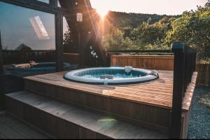 a hot tub on a deck with the sun in the background at Valdo Cabin in Sadu