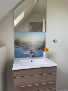 a bathroom sink with a painting on the wall at Haus-Seeschwalbe-Wohnung-2 in Nieblum