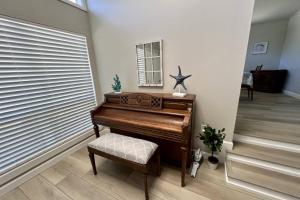 a brown piano in a hallway with a chair and a mirror at Cathy and Jim's Florida Beach House in Fort Walton Beach