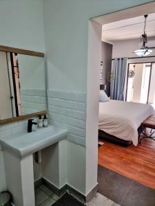 een badkamer met een wastafel en een bed in een kamer bij Sonskyn Hof Guest House / Gastehuis in Jan Kempdorp
