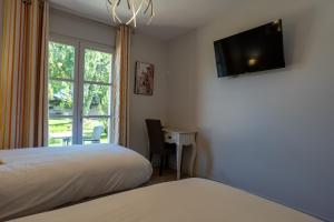 a bedroom with a bed and a desk and a television at Hotel Village Motel in Tournus