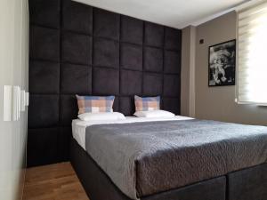 a bedroom with a large bed with a padded headboard at SkopjeLUX Apartments in Skopje