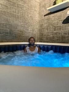 eine Frau, die in einer Whirlpool-Badewanne sitzt in der Unterkunft Hôtel La Belle Etoile & SPA in Saly Portudal