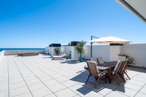 une terrasse avec une table, des chaises et un parasol dans l'établissement Hauzify I Apartaments Roques Daurades, à L'Ametlla de Mar