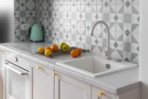 a kitchen counter with a sink and fruits on a rack at Lion Apartments -Juicy Sopot Premium Familly Stay 200 m from the sea in Sopot