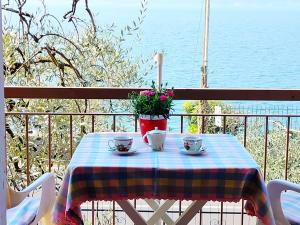 a table with two cups and flowers on a balcony at Lorena house in Brenzone sul Garda