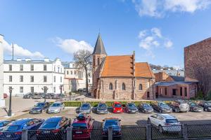 um grupo de carros estacionados num parque de estacionamento em frente a uma igreja em Kaunas Heart Apartment em Kaunas
