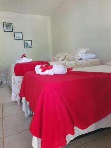 a bedroom with two beds with red and white blankets at Pousada Shalon Adonai Noronha in Fernando de Noronha