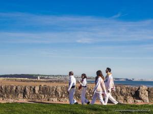 a group of people walking along a wall near the beach at Coney Cottage in Porthcawl
