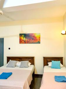 two beds in a room with a painting on the wall at Marathona Tourist Resort - Anuradhapura in Anuradhapura