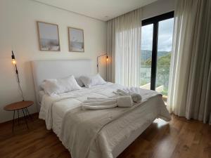 a white bedroom with a bed with towels on it at Casa 08 Monte Boa Vista - Piscina Privativa, Sauna e Ofurô de Imersão in Teresópolis +35 photos