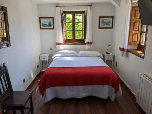 a bedroom with a large bed with a red blanket at Posada Revolgo in Santillana del Mar