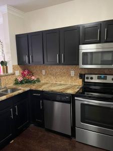 a kitchen with black cabinets and stainless steel appliances at Pink Tulum Houston 2min from Galleria in Houston