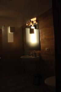 a dark bathroom with a sink and a mirror at Hotel Dia Lin in Borşa