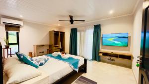 a bedroom with a bed and a flat screen tv at Le Port Guest House in Baie Sainte Anne