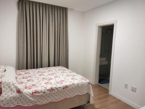 - une chambre avec un lit et une couverture fleurie dans l'établissement Apartamento luxo Meia Praia, à Itapema