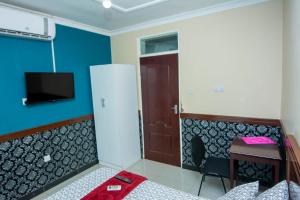 a room with a bed and a desk and a refrigerator at Cherries Egul Lodges in Lilongwe