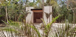a building with a door in the middle of a forest at MBH Maya Bacalar Hotel Boutique in Bacalar