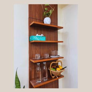 a wooden shelf with bottles and a basket of fruit at Iranyai Homestay in Imphal