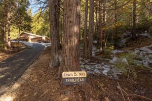 un panneau sur un arbre à côté d'une route dans l'établissement Sugarpine Trailhead Lodge at Lewis Creek Upper Trailhead just 7 miles from Yosemite, à Oakhurst