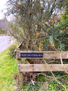 a wooden bench with a sign that reads wet slippery equipment at Wee Silverburn in Whiting Bay