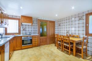 una cocina con armarios de madera, mesa y sillas en Villa Can Soler, en Alcudia