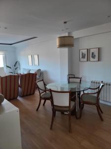 a dining room with a glass table and chairs at Ático con terraza in Vigo