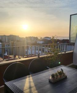 d'une table et de chaises sur un balcon avec vue sur le coucher du soleil. dans l'établissement Ático con terraza, à Vigo