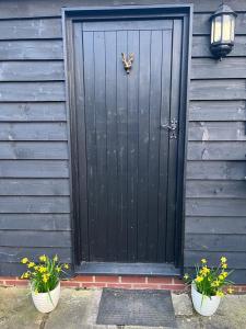 a black door with two potted plants in front of it at Two Storey Annex in Cottenham