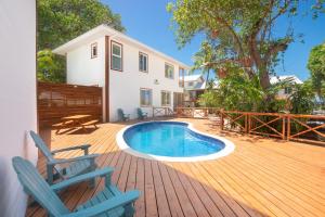 a deck with a pool and two chairs and a house at Casa Coral home in Roatan