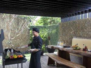 a man holding a plate of food on a grill at Villa Hana in Canggu
