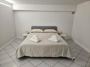a white bedroom with a large bed with two tables at REGINA Loft in Ospedaletti
