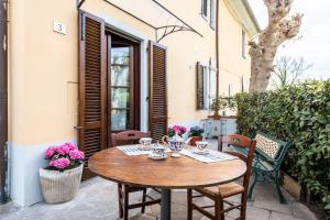 Une table et des chaises en bois sont disponibles sur la terrasse. dans l'établissement Homiday - Tuscany House - Parcheggio e Giardino Privato, à Pise